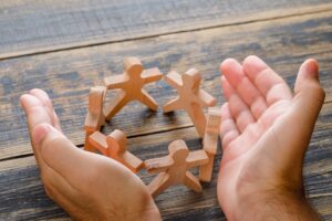 concetto-di-successo-di-affari-sulla-vista-di-legno-del-piano-d-appoggio-mani-che-proteggono-figure-in-legno-di-persone